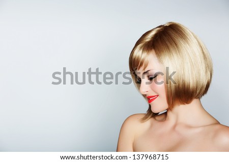 portrait of a beautiful woman in short blond bob with bright make-up on studio background