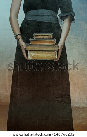 Closeup Of Antique Torn Books With A Hands Of A Young Woman Held Against Black Dress On A Grunge Textured Background
