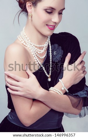 beautiful girl wearing vintage velvet dress with expensive pearl necklace on studio background