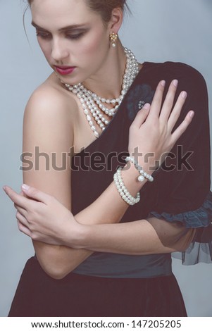 beautiful girl wearing vintage velvet dress with expensive pearl necklace on studio background