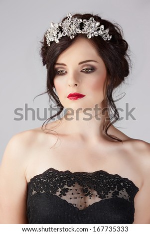Beautiful brunette young bride with braided hair with shiny crown wearing black lace dress in studio