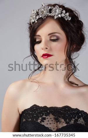 Beautiful brunette young bride with braided hair with shiny crown wearing black lace dress in studio
