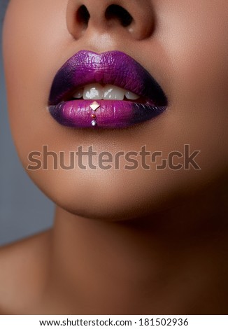Close-up of woman's lips with dark fashion purple lipstick with ombre effect on a tanned face
