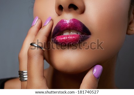 Close-up of woman\'s mouth with dark fashion purple lipstick with ombre effect. Hand with purple nailpolish touching tanned face