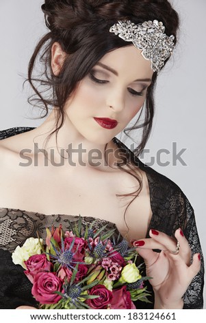 Beautiful brunette young model with braided hair with shiny crown wearing black lace dress in studio