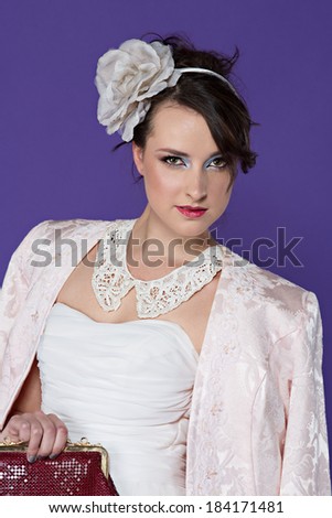 Beautiful young bride wearing vintage pastel jacket and white lace collar with flower hair band on purple studio background