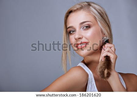 Portrait of blond cheerful woman with straight hair and natural makeup on grey studio background