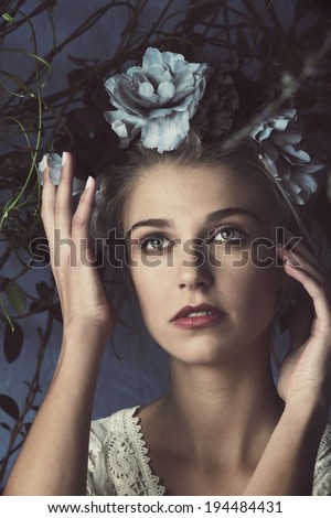 Portrait of a beautiful woman with natural makeup. Wearing silk flower headpiece on grunge plant background