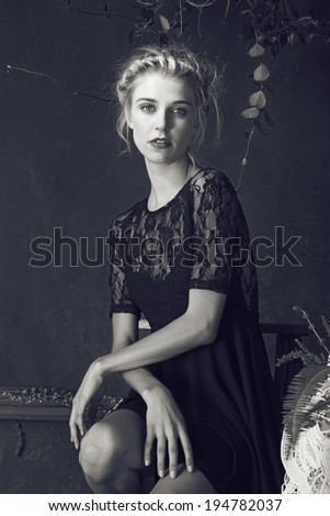 Beautiful blond woman with braid hairstyle and natural makeup. Wearing ping bohemian sequin and feather dress. Against blue grunge background