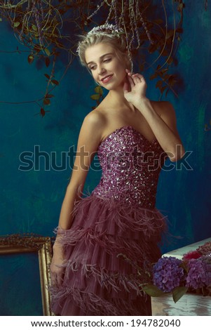 Beautiful blond woman with braid hairstyle and natural makeup. Wearing ping bohemian sequin and feather dress. Against blue grunge background
