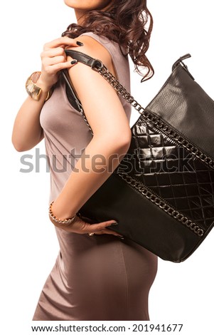 Closeup of woman with quilted fashion leather black bag with chains. Isolated on the white studio background.