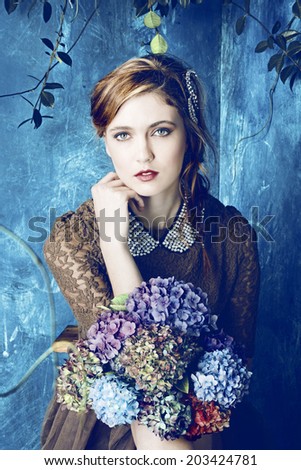 portrait of a beautiful woman with red hair in curly braided hairstyle. wearing a romantic lace dress and holding flowers on grunge painted background