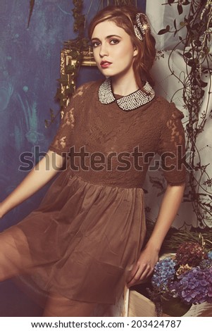 portrait of a beautiful woman with red hair in curly braided hairstyle. wearing a romantic lace dress with pearl collar on grunge blue background