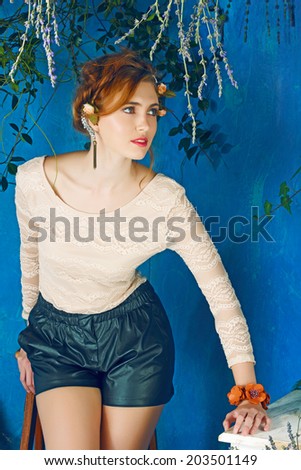 portrait of a beautiful woman with red hair in braided hairstyle. wearing leather shorts and lace top on grunge painted background