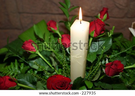 White candle in a bunch of red roses