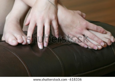 woman\'s bare feet and hands on a leather cushion