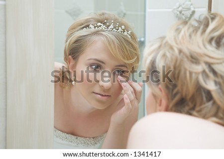Reflection of a young woman in wedding dress fixing her make-up