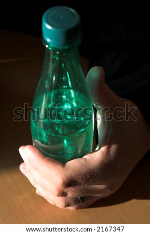 Man holding a plastic mineral water bottle in natural light