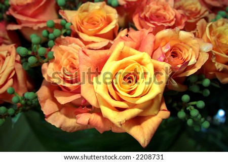  yelloworange roses arranged with green berries at a wedding reception