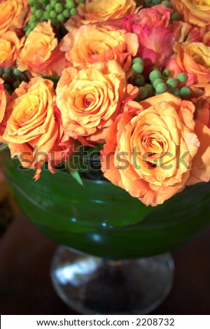  yelloworange roses arranged with green berries at a wedding reception