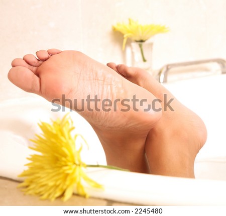 Feet of a tanned young woman sticking out of the bath-tub