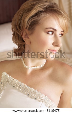Beautiful bride with short blond hair in pearl beaded dress and soft make-up