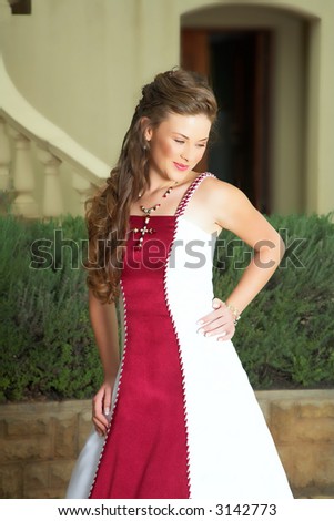 Beautiful smiling young bride in red & white dress,  long curly hair in afternoon sun