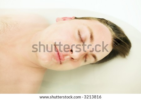 Young man in the bath with whole body under clean body and half face is out. Focus on the eye, shallow DOF