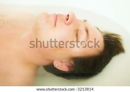 Young man in the bath with whole body under and face is out. Focus on the nose, mouth, shallow DOF