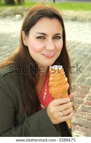 Beautiful woman with long brown hair and smile eating caramel ice-cream . ISO 125, no sharpening