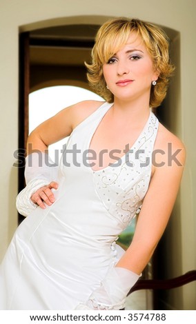 Beautiful blond bride with short hair, in white halter neck dress, bead embroidery