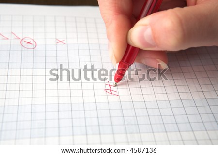 Woman teacher marking a test paper with an A+, holding a red pen, shallow depth of field with focus on the A.