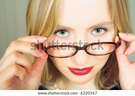 Young blond businesswoman looking over her black rim glasses
