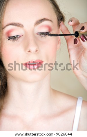 Beautiful young woman with natural make-up with mascara applied by make-up artist