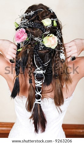 young bride with long brown hair braided with roses and beads in complex design wearing white corset wedding dress