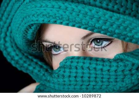 Young woman with black kohl make-up on eyes in traditional Middle East fashion covering her face with green scarf
