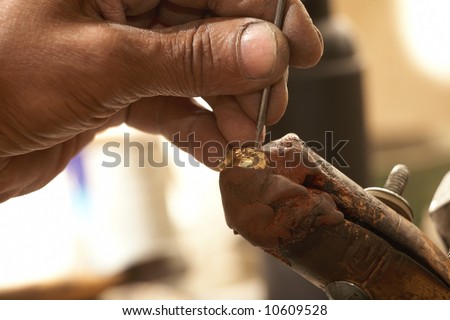 Goldsmith working on an unfinished 22 carat gold ring with his hard working hands