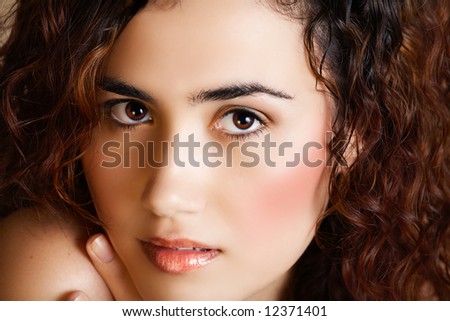 young woman with brown curly hair and golden fashion make-up in her 18-20s