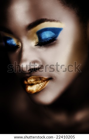 African woman with gold and blue metallic make-up and full shiny lips