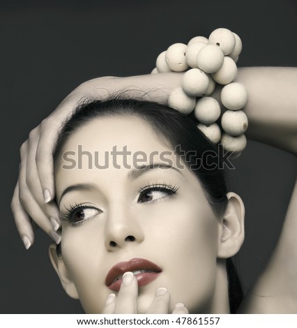 beautiful brunette woman with classic make-up and wooden beads on her hand in vintage finish