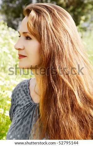 Pretty middle aged casual woman with natural color long red hair in the green field