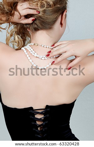 beautiful woman wearing a corset and white pearls from the back.