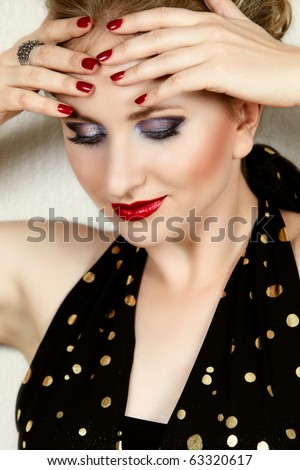 beautiful woman with fashion make-up in black and gold dress looking down