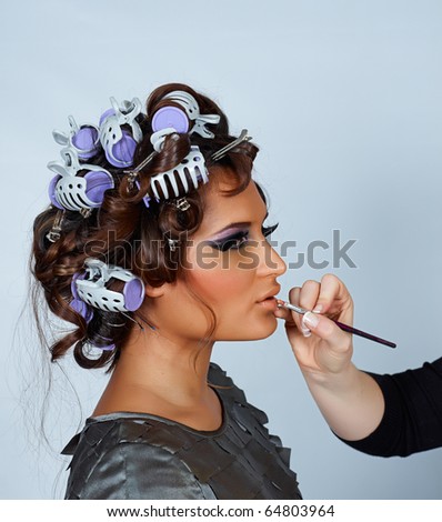 beautiful young latina model with her hair in curlers and make-up done before  fashion shoot, with space for text