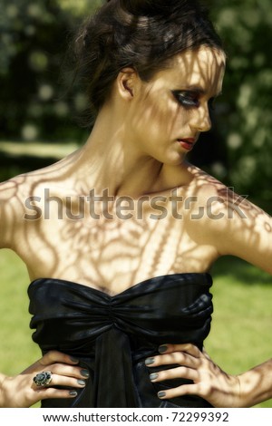 beautiful young woman with dramatic red eyeshadows and false lashes with lace shadow over her face and body