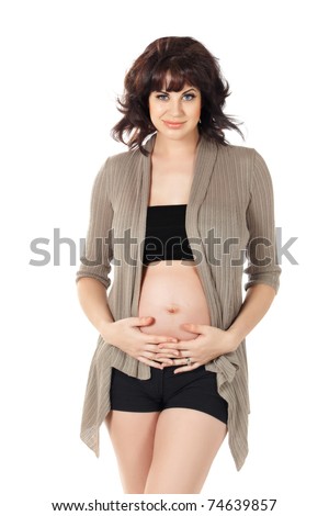 beautiful pregnant brunette woman in early stages of her pregnancy wearing open cardigan and shorts over white background.