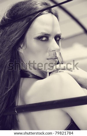 beautiful young woman with long dark hair wearing dark eyeshadow looking over her shoulder in retro finish