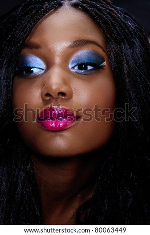 beautiful African woman portrait with bright pink lips and dark artistic eyeshadow with long extensions hairstyle in low key light