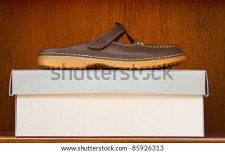 stylish brown leather slip on shoe with rubber sole on a box in a wooden shelf display with copy space.