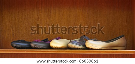 five new summer comfortable shoes in leather and rubber on display on a wooden shelf with copy space - focus on stitched brown shoe.
